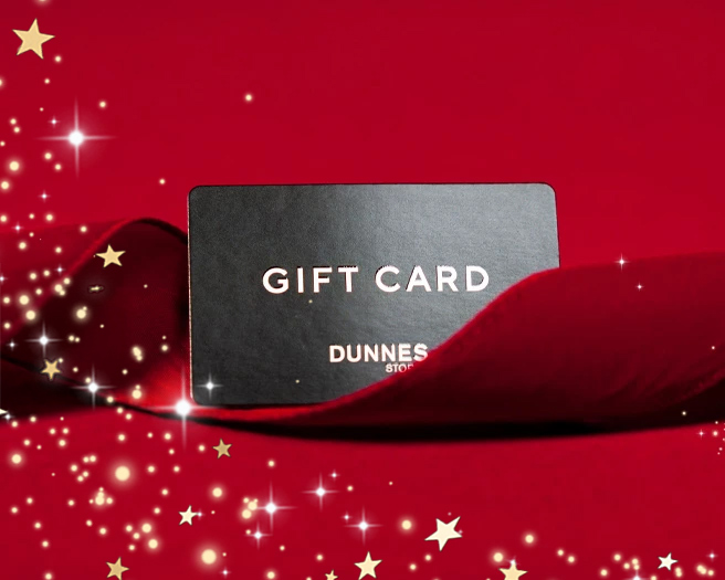 A gift card labeled "Gift Card Dunnes Stores" sits on a red velvet background, surrounded by sparkling stars, evoking a festive and elegant mood.