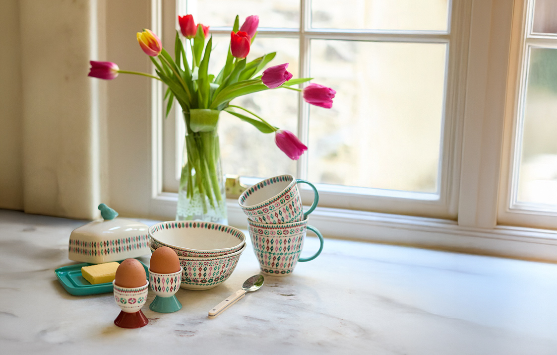 A table featuring a vase of colorful flowers and a bowl of eggs, creating a warm and inviting atmosphere.